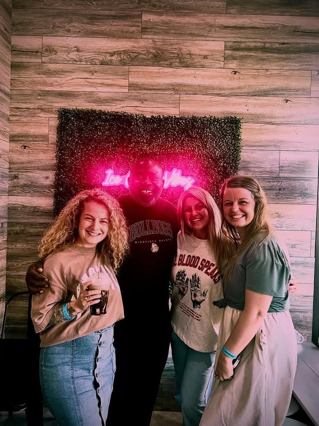Friends gathered at the Smile neon wall